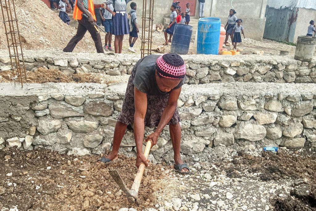 A community member in Massan, Haiti helps to build a new school with buildOn.