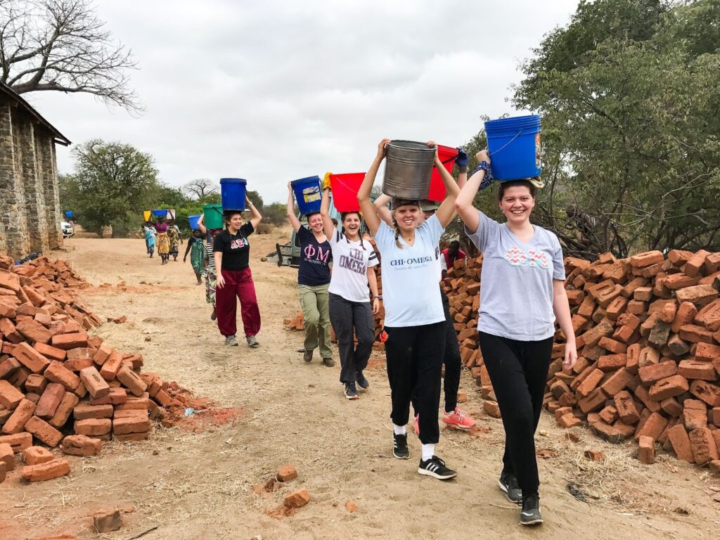 Sorority women from Tulane University carry buckets of water on the worksite in Mwanzolo, Malawi.
