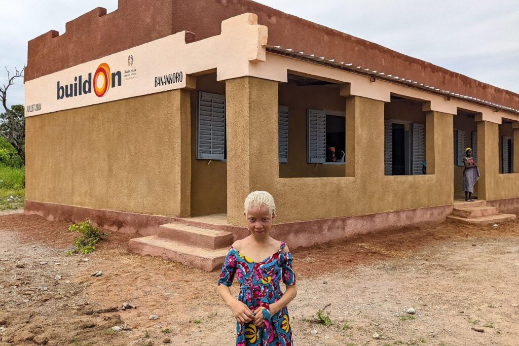 Maimouna, standing in front of her brand new school, was excluded from education because of her albinism, like many others in sub-Saharan Africa.