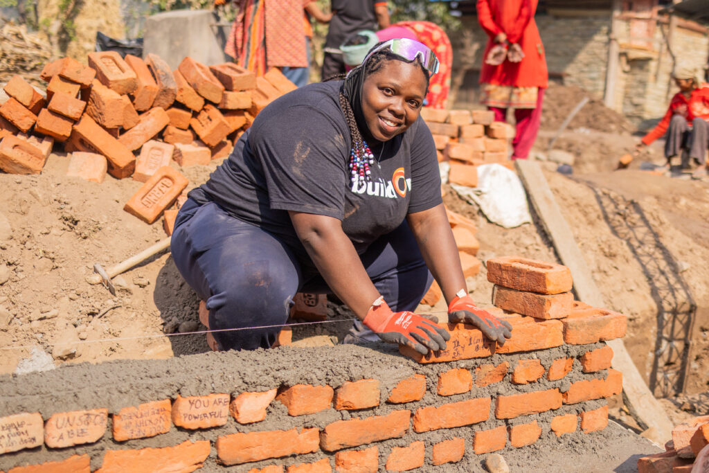 buildOn alum Hadassah Williams lays bricks for a new school in Museti, Nepal.
