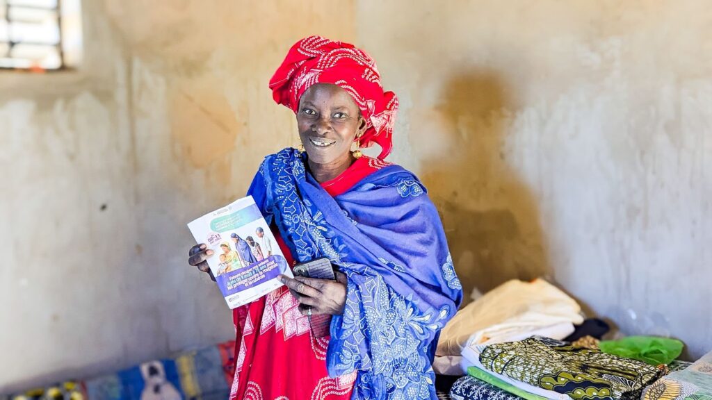 Awa proudly holds up her public health booklet, which she uses to educate her community.
