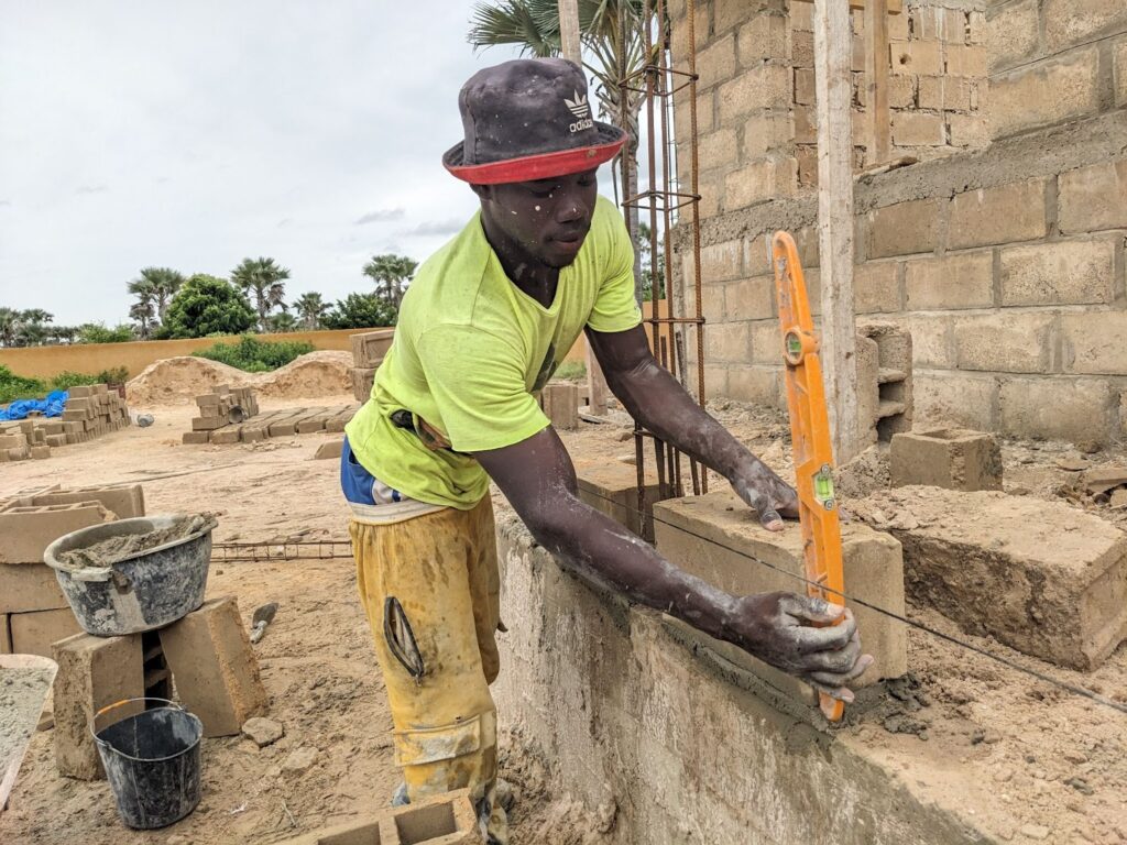 One of our masons carefully lays bricks for a new school in Senegal.