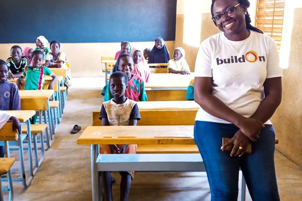 Jocelyne Tenkouano, our Country Director in Burkina Faso, stands in front of a brand new classroom full of students.