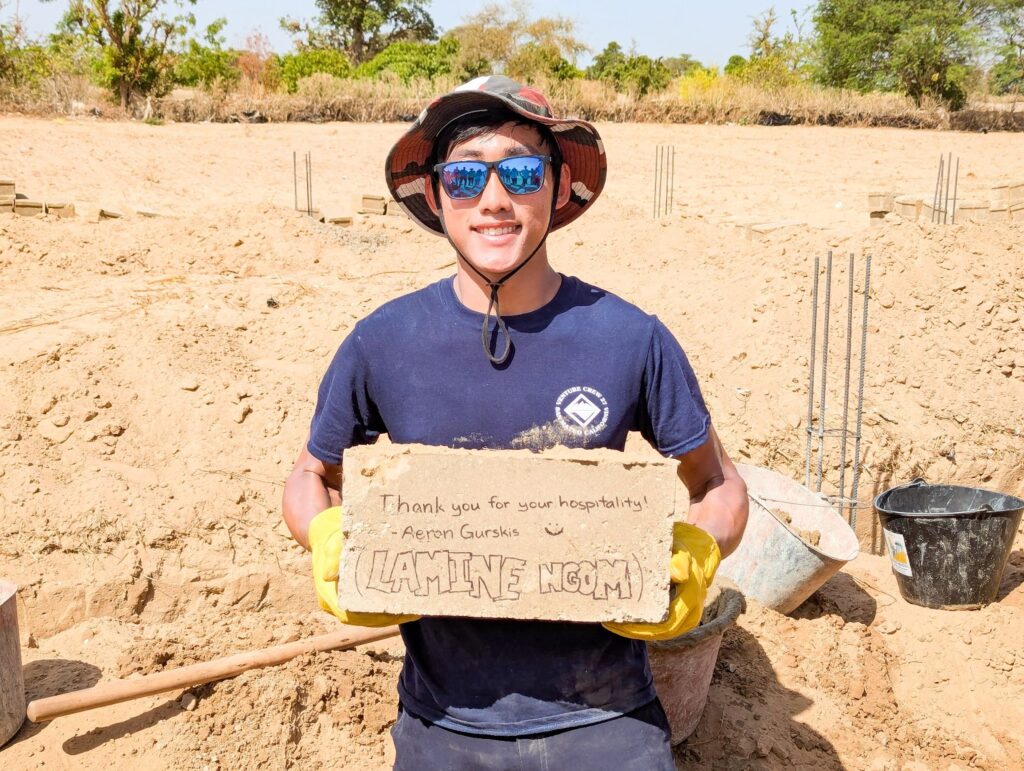 Aeron poses with a signed brick for the walls of the new school, a Trek tradition.