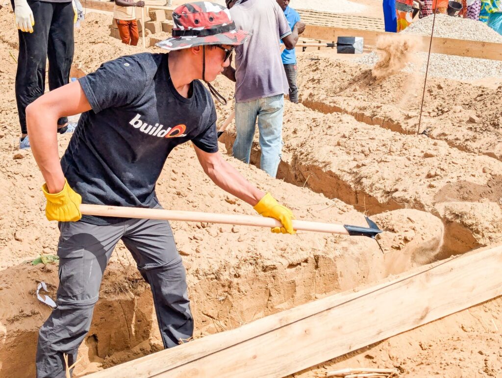 Aeron helps to dig the foundation for the brand new school.