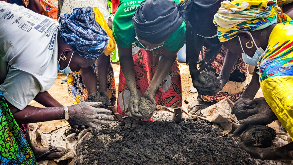 The people of Nerane Diarrere work together to mix the clay for their new stoves.
