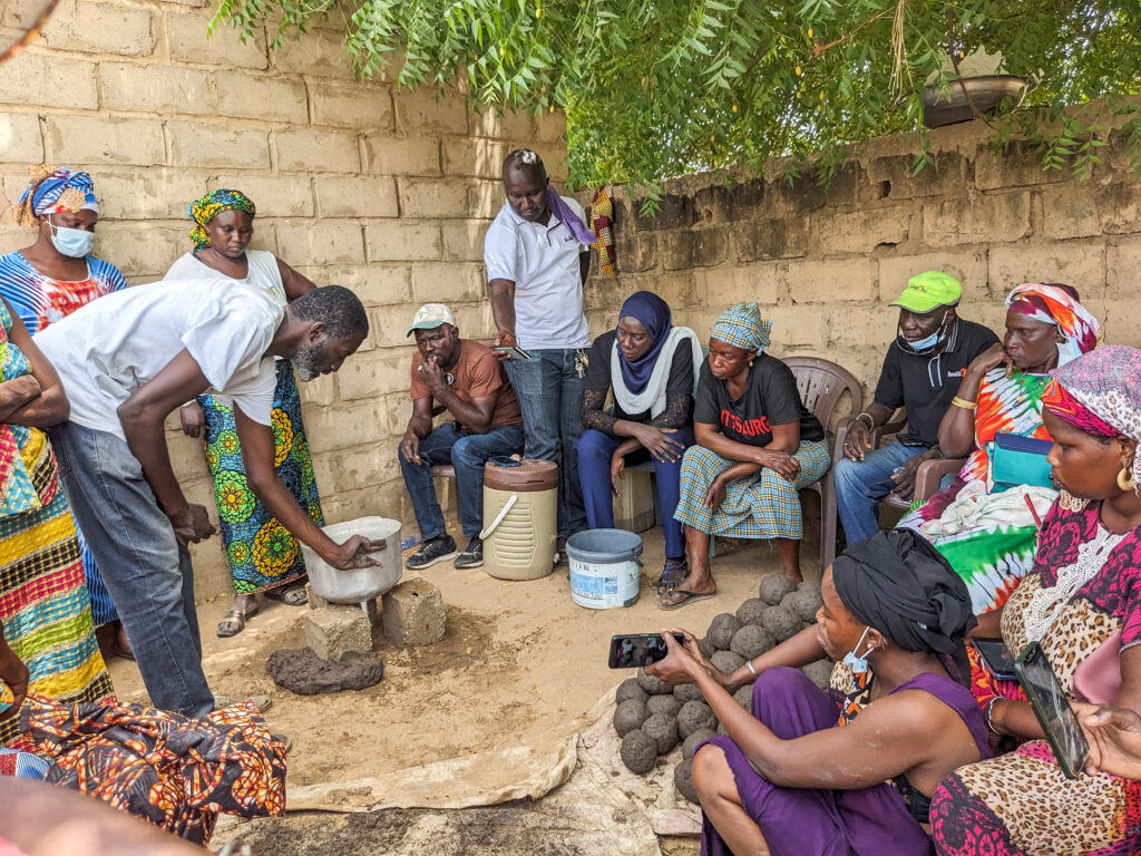 A buildOn staff member shows participants how to use the balls to build the base of the stoves.