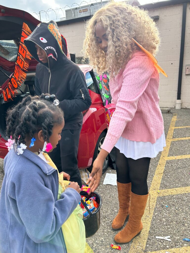 East English Village Prep 11th-grade class president Eriona Long helps hand out candy at the Trunk-or-Treat.