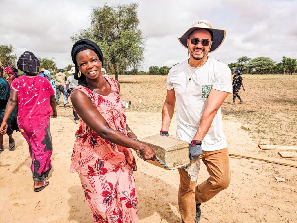 A Trek participant helps carry bricks in Senegal.
