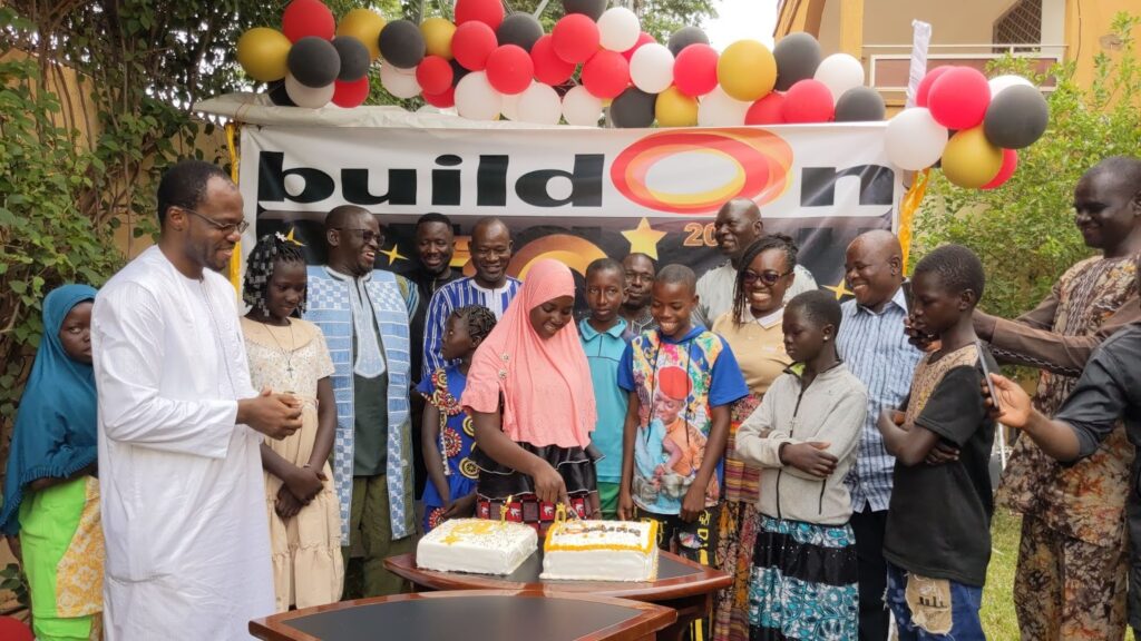 Nassiratou Nikiéma helps cut the cake at buildOn’s 10 year anniversary celebration in Burkina Faso.