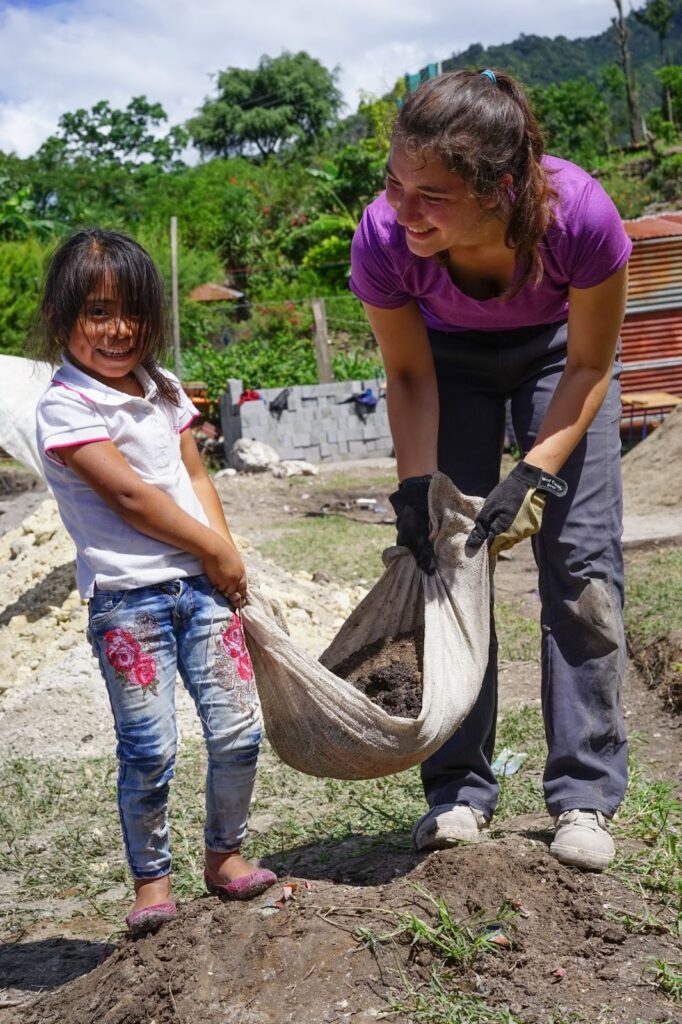 A Trek participant works side-by-side with a girl who will attend the school they built together.