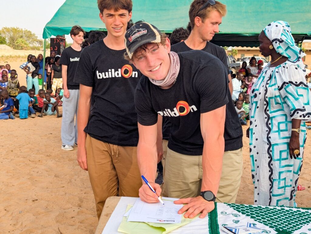 Pine View buildOn Club Co-President Noah Stewart signs a buildOn covenant in Senegal.