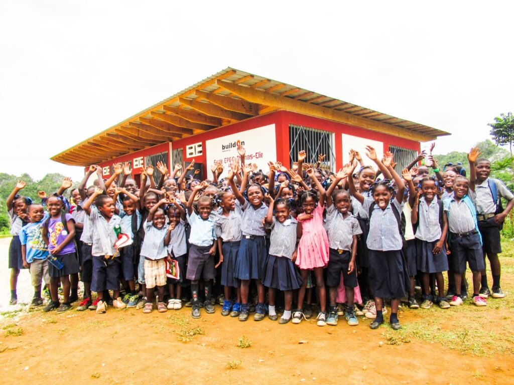 Students in Thomas Elie, Haiti, celebrate in front of the new school Sarah helped build.