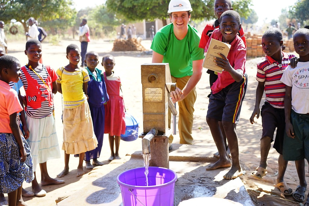 A Trek participant helps pump water to bring to the worksite in Malawi.