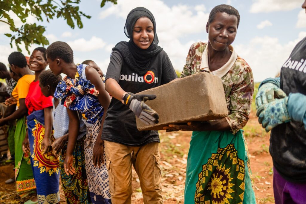 Trek participants and community members pass bricks on the worksite in Malawi.