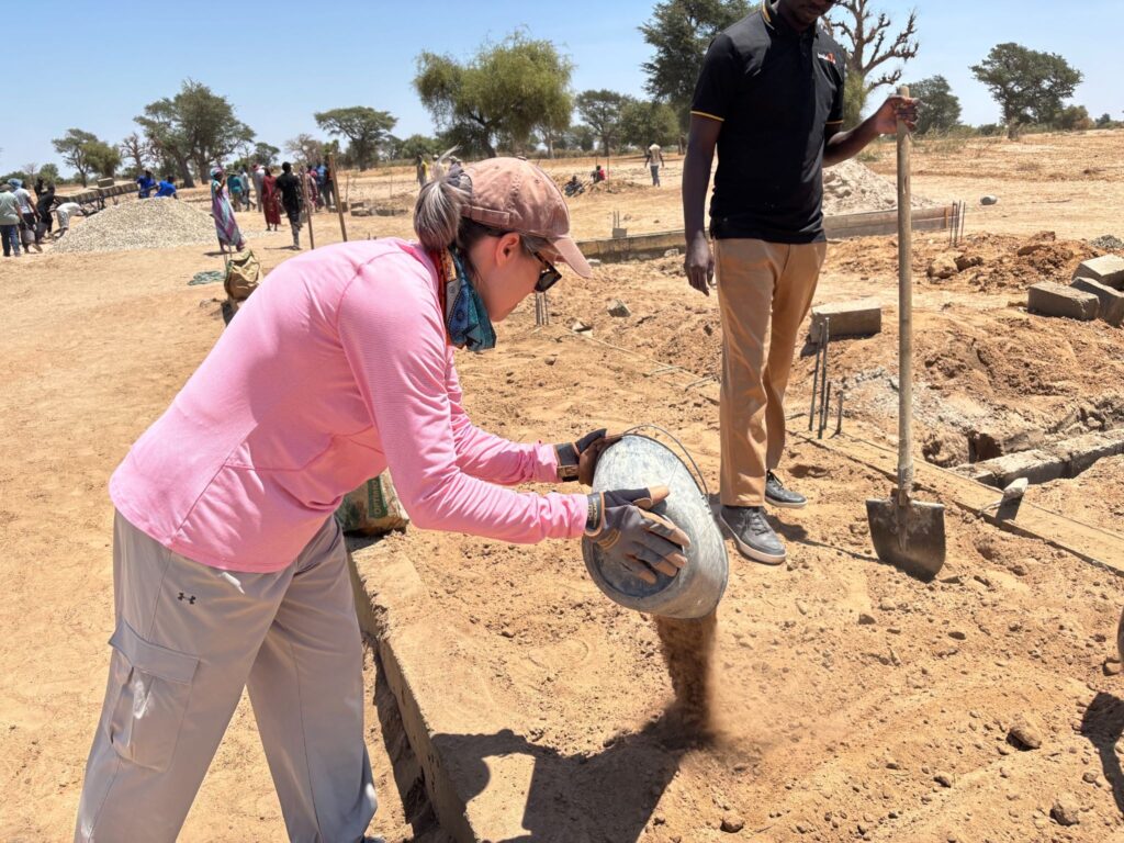 Senior Vice President of Enterprise Initiatives Kathy Vogt helps pour dirt for the school’s foundation.