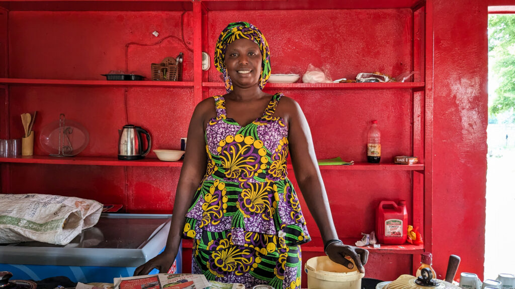 An Adult Literacy Participant in Gatte proudly displays her goods at the convenience store she was able to start using seed money from the program.