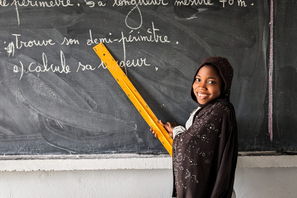 A girl in Keur Walfatma, Senegal practices reading at the blackboard in her new buildOn school.