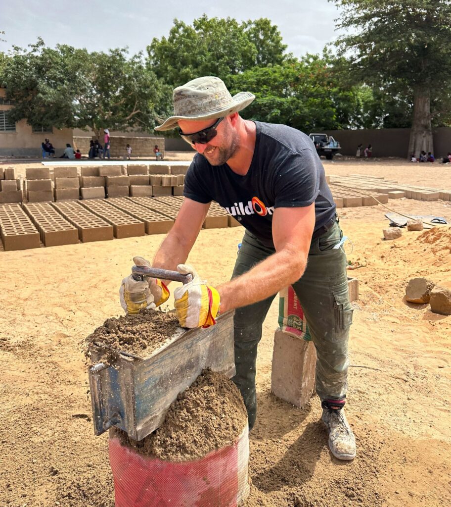 A buildOn Trek participant helps make bricks in Senegal.