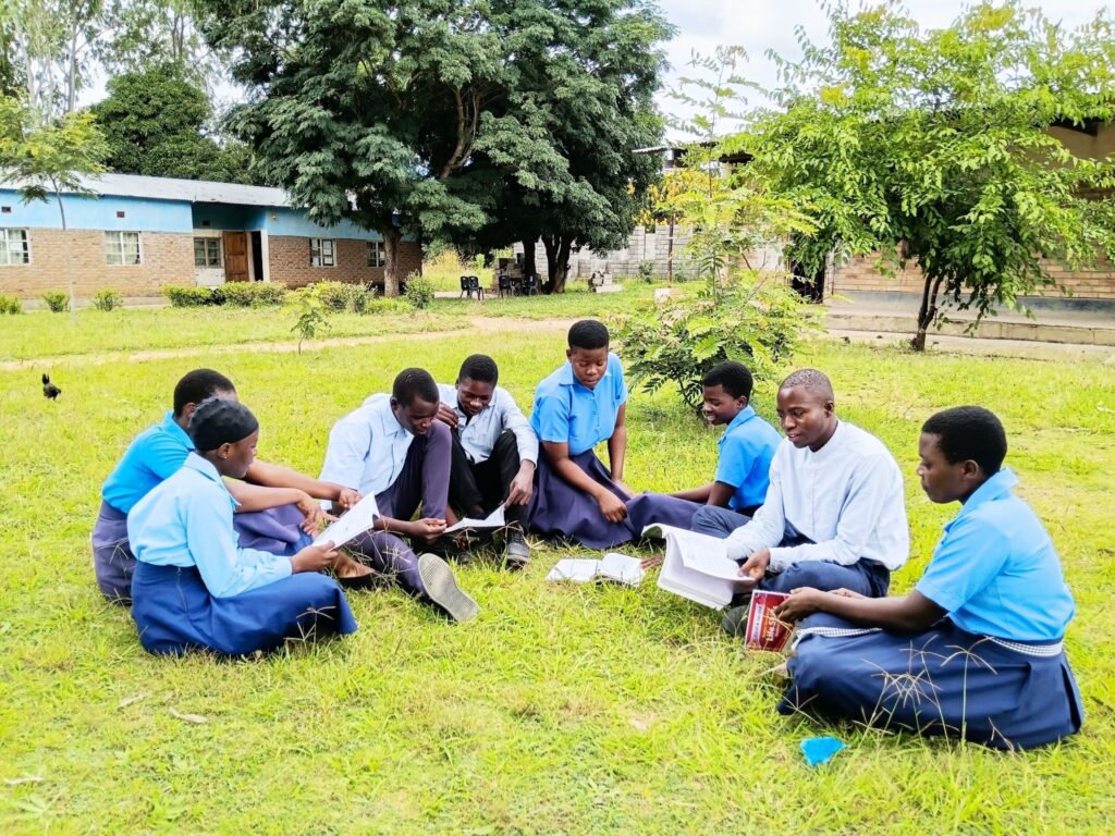 Patrick (second from right) sits with his classmates outside of his secondary school.