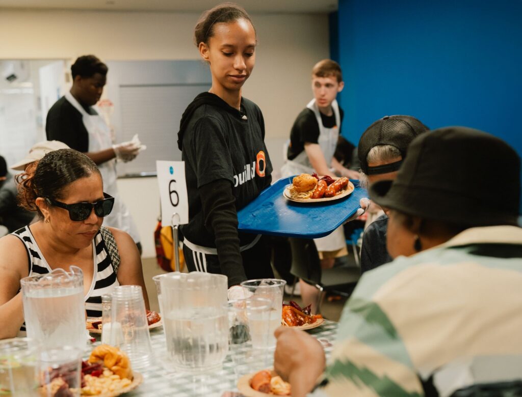 A buildOn student helps pass out food at Part of the Solution (POTS) in the Bronx.