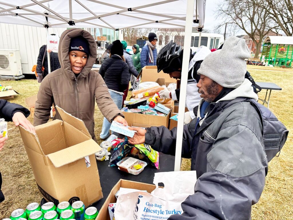 A buildOn student in Detroit distributes food at Avalon Village.