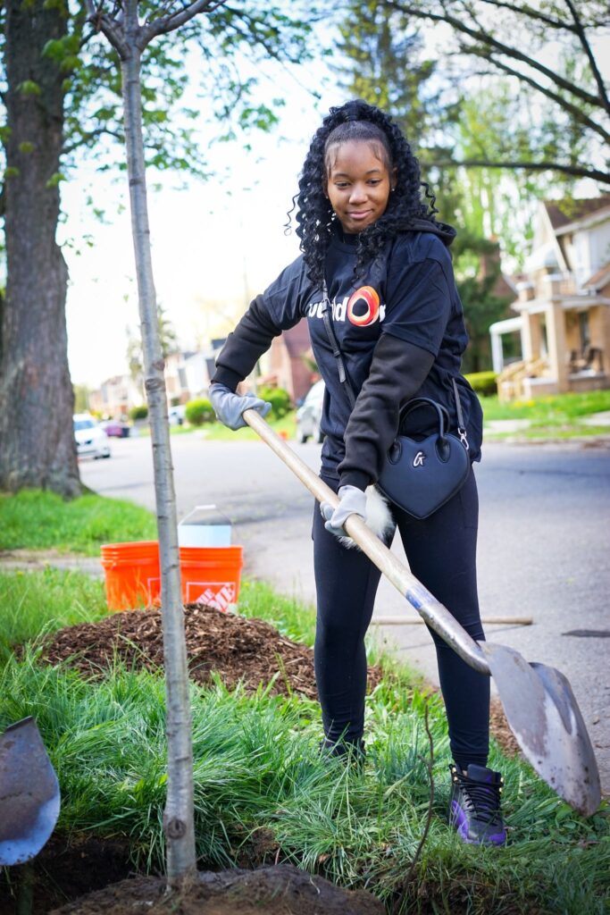 A buildOn senior from Detroit Pershing High School helps plant a tree.
