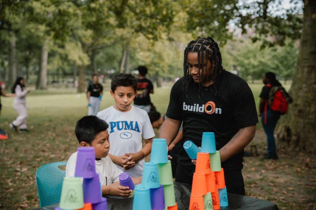 A buildOn student helps out at a family event at St. James Park in the Bronx.