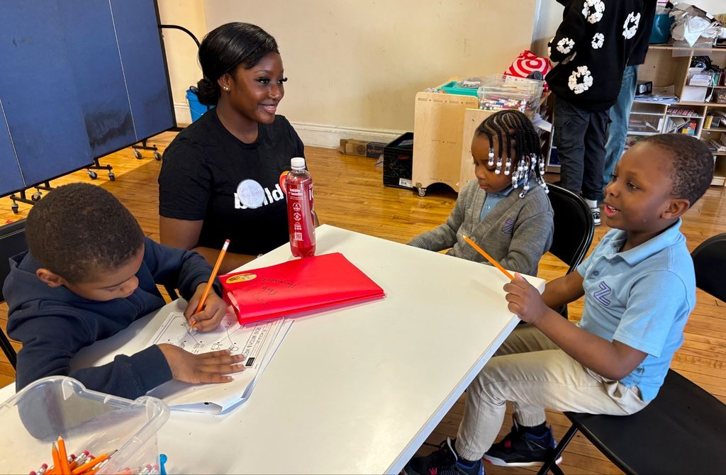 A buildOn student helps tutor younger students at A House on Beekman in the Bronx.