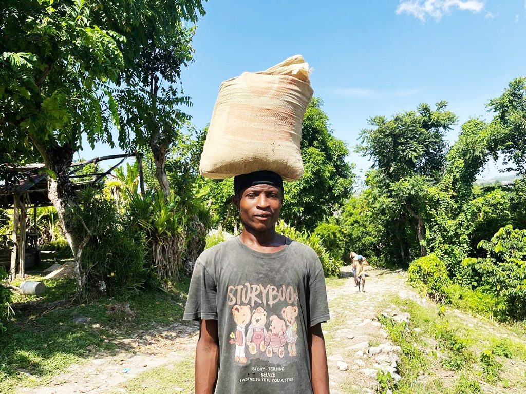 A community member in Navarre carries construction materials for the new school on his head.